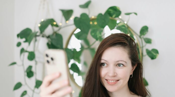 What Are the Environmental Benefits of VoIP? Woman using phone mirror and green plant in background