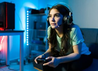 Can Full Fibre Broadband Reduce Latency in Online Gaming? Girl sitting on a couch gaming with headphones on her head surrounded by blue lights