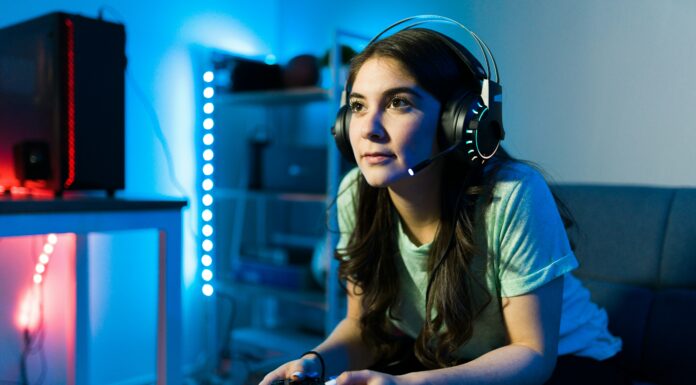 Can Full Fibre Broadband Reduce Latency in Online Gaming? Girl sitting on a couch gaming with headphones on her head surrounded by blue lights