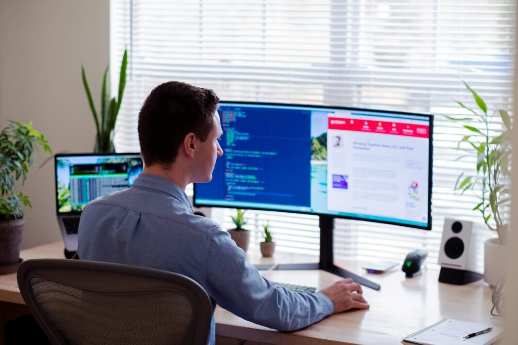 A man sitting in his home office doing work ons his computer.