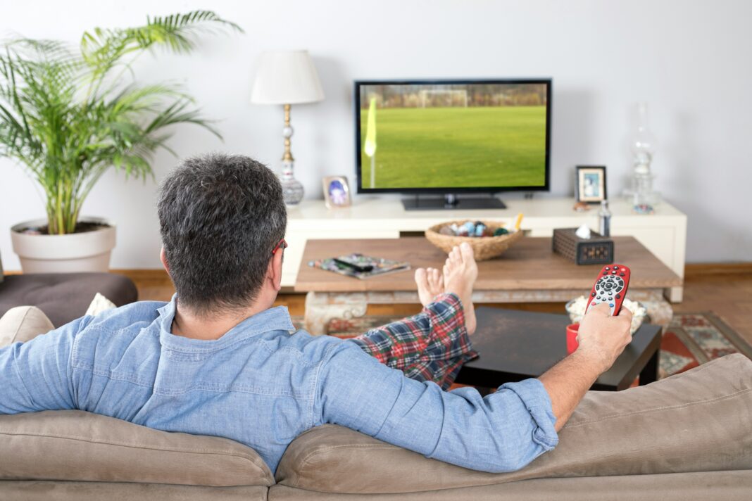 How Does Mobile Broadband Enable Real-Time Video Streaming? A man sitting on a couch streaming a video with the remote in his hands.