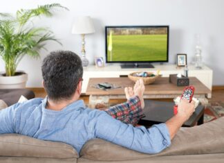 How Does Mobile Broadband Enable Real-Time Video Streaming? A man sitting on a couch streaming a video with the remote in his hands.