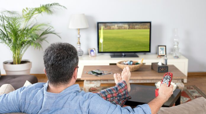 How Does Mobile Broadband Enable Real-Time Video Streaming? A man sitting on a couch streaming a video with the remote in his hands.