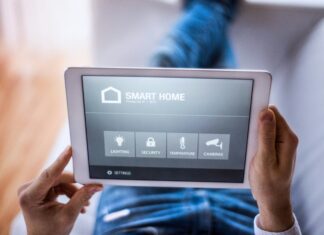 How Does VoIP Contribute to the Development of Smart Homes? Unrecognisable hand holding a tablet with a smart home app opened on it.