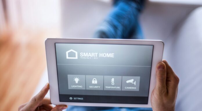 How Does VoIP Contribute to the Development of Smart Homes? Unrecognisable hand holding a tablet with a smart home app opened on it.