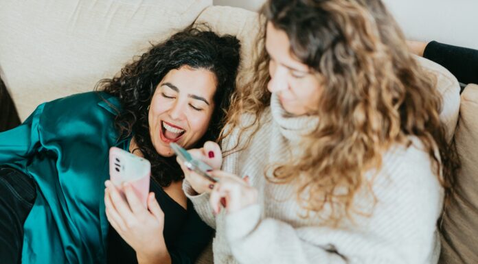 How Does VoIP Integration with Social Media Platforms Enhance Customer Engagement? Two friends sitting on a couch laughing while scrolling through social media