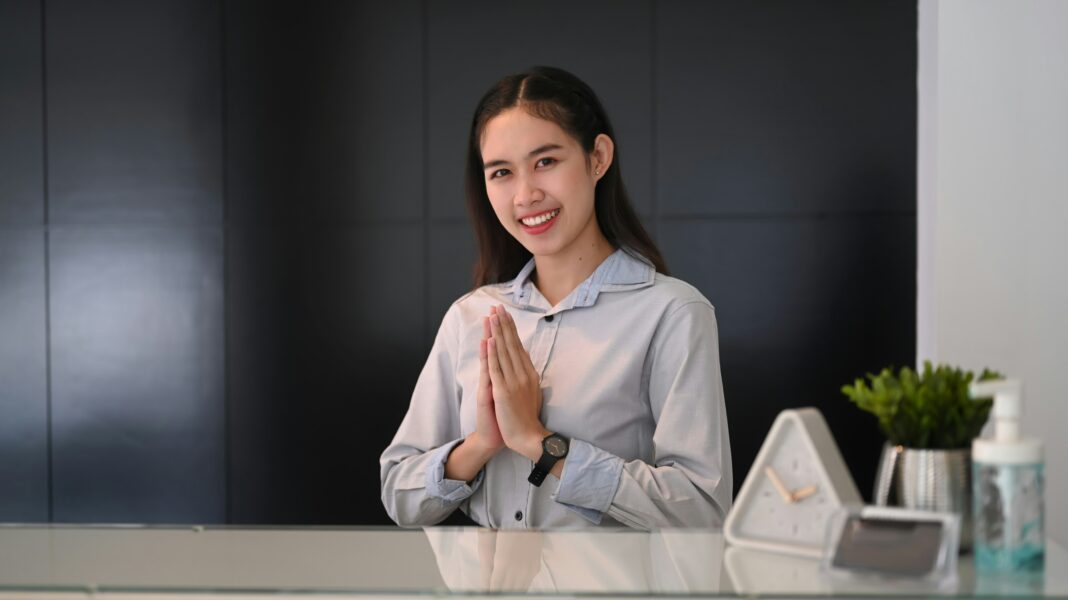 Woman working behind a desk in a hotel greeting guests.