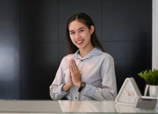 What Are the Unique Benefits of VoIP for the Hospitality Industry? Woman working behind a desk in a hotel greeting guests.