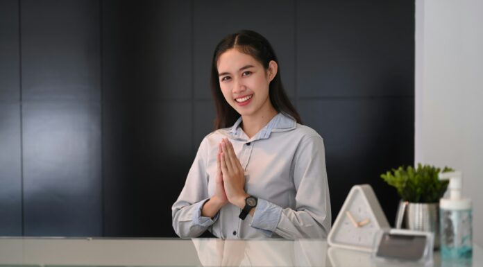 What Are the Unique Benefits of VoIP for the Hospitality Industry? Woman working behind a desk in a hotel greeting guests.