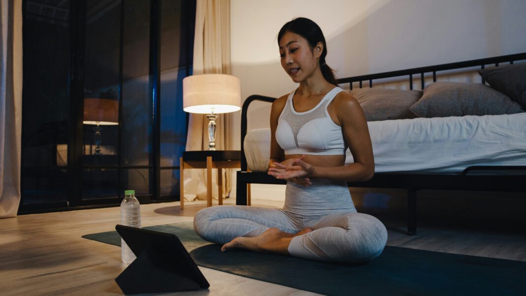 Can Broadband Internet Bridge the Urban-Rural Digital Divide? A woman sitting on the ground doing yoga while streaming a video on her tablet