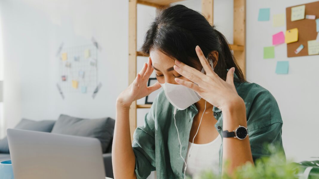 Woman sitting at her desk in front of her laptop with a mask on