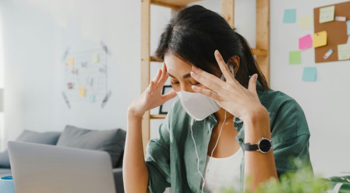 Can VoIP Really Transform Your Business Operations? Woman sitting at her desk in front of her laptop with a mask on