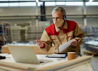 Do You Need New Phones to Use VoIP for Business? Man sitting at his desk with his computer and a mask on face having a meeting