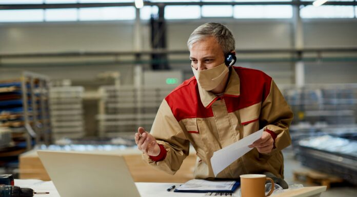 Do You Need New Phones to Use VoIP for Business? Man sitting at his desk with his computer and a mask on face having a meeting
