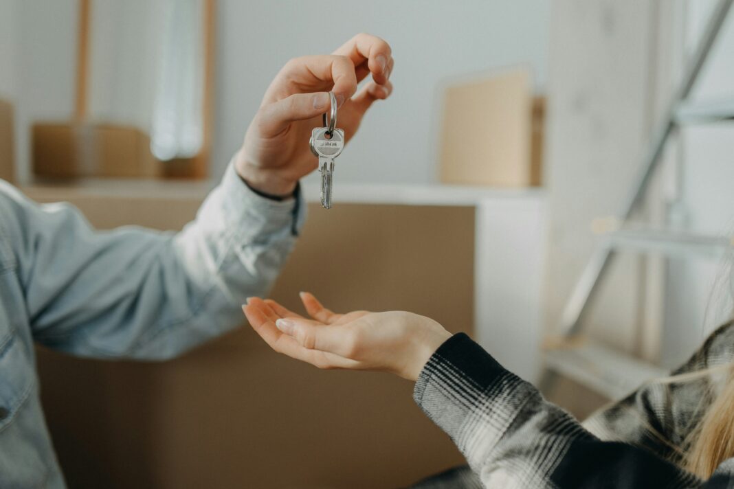 How Does Broadband Availability Influence Real Estate Investment? Photo of a person handing the keys of a new house to someone else
