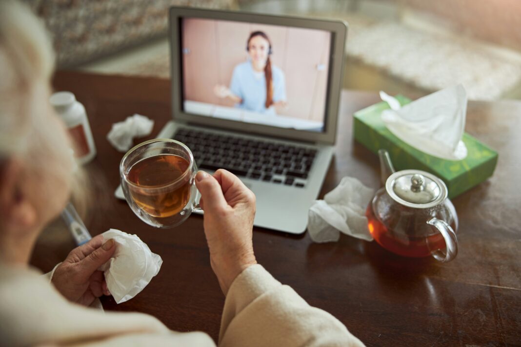 Someone consulting a dr online from their home while drinking tea
