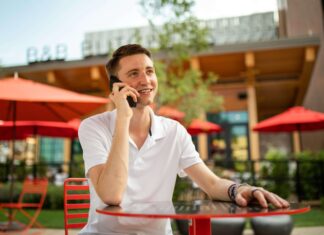 Are VoIP Phones Expensive? A man sitting outside a shop at a table talking on his phone