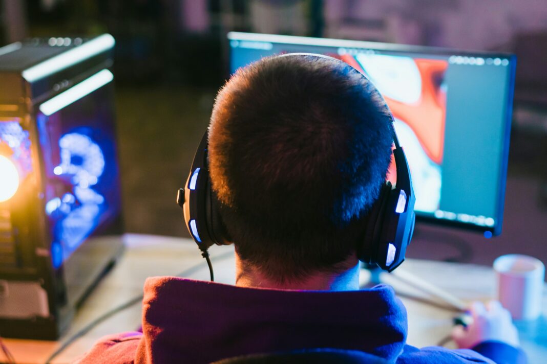 Man sitting at his desk playing games with his headphones on
