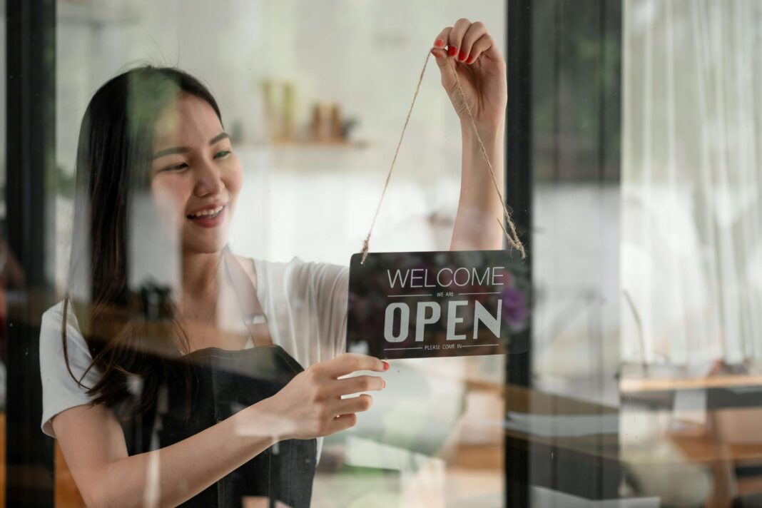 A woman smiling while changing the open sign on her business