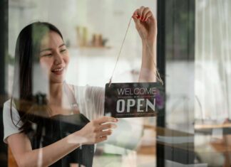 Top Reasons to Use VoIP for Your Small Business A woman smiling while changing the open sign on her business