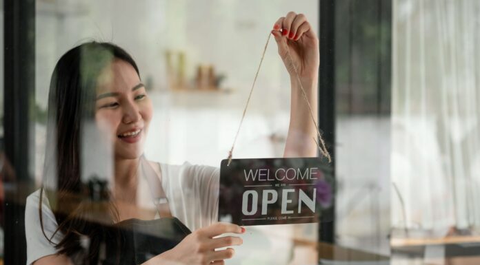 Top Reasons to Use VoIP for Your Small Business A woman smiling while changing the open sign on her business