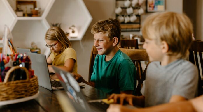 What Are the Economic Benefits of Broadband Investment? Three children sitting at a table with their laptops doing work