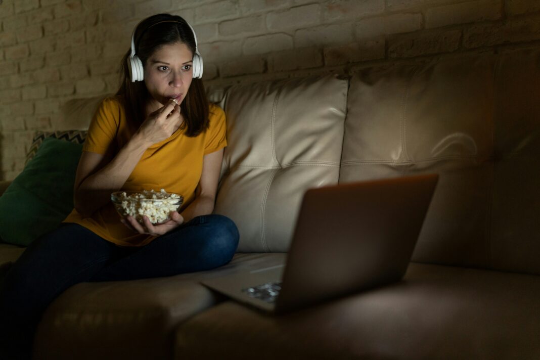 What is Full Fibre Internet? A woman sitting on her couch eating popcorn while watching a movie on her laptop