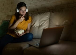What is Full Fibre Internet? A woman sitting on her couch eating popcorn while watching a movie on her laptop