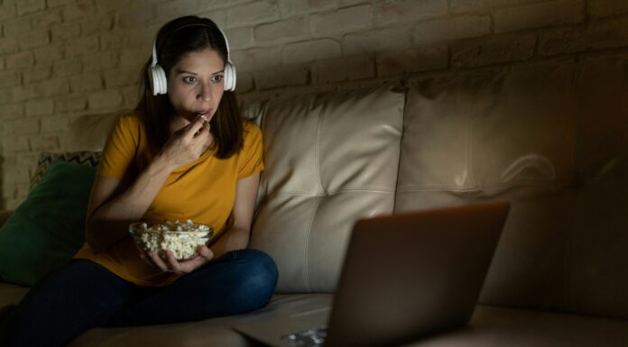 What is Full Fibre Internet? A woman sitting on her couch eating popcorn while watching a movie on her laptop