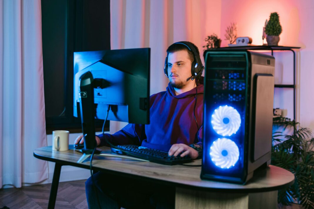 A man sitting at his desk in front of his screen with a headset on
