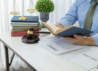 7 VoIP Benefits for Legal Practices A man reading a book while sitting at his desk with a gavel laying next to him