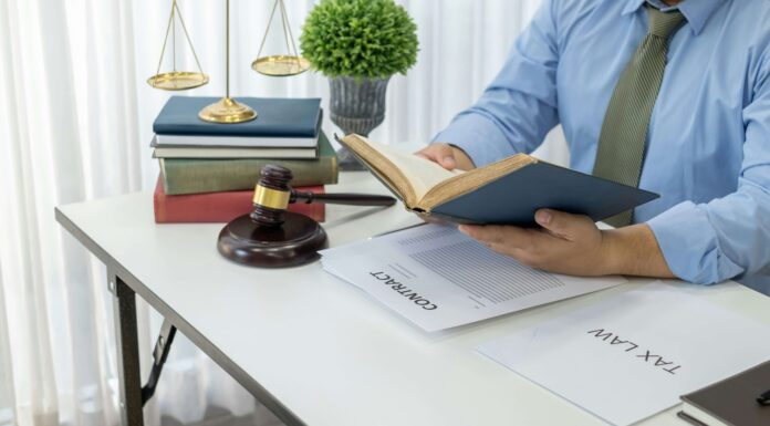 7 VoIP Benefits for Legal Practices A man reading a book while sitting at his desk with a gavel laying next to him