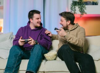 Can I Use VoIP With Starlink? Two men sitting on a couch with gaming remotes laughing