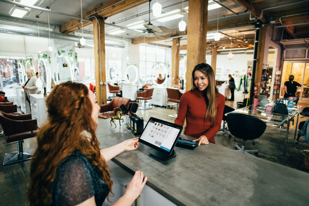 A woman standing behind the register helping a customer