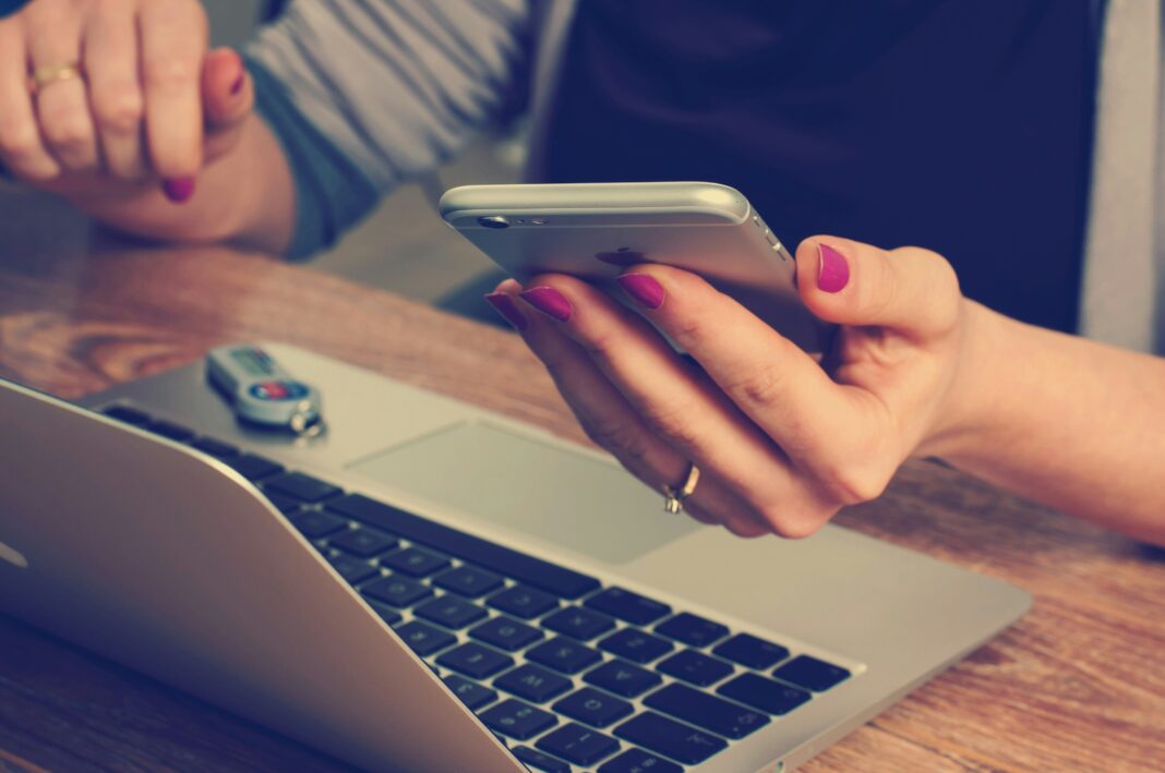 Is Mobile Broadband as Good as Fibre? A woman sitting in front of her laptop while typing on her phone