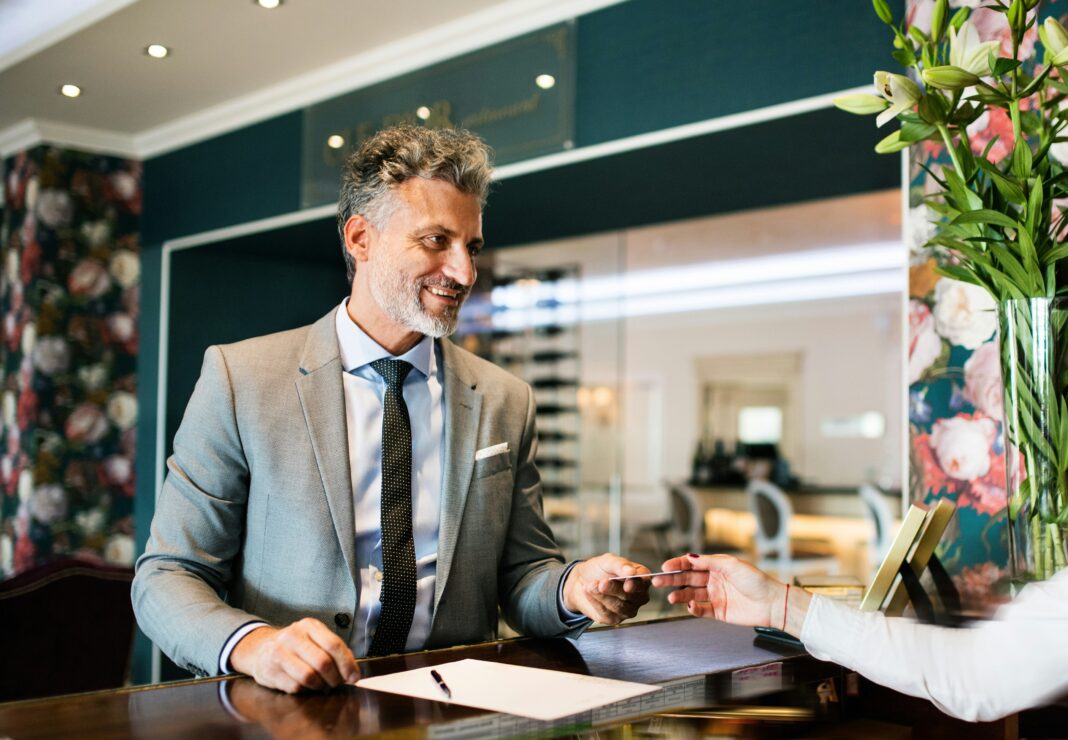 The Benefits of Full Fibre for UK Hospitality Businesses A man standing behind a desk giving a card back to a client