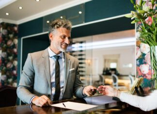 The Benefits of Full Fibre for UK Hospitality Businesses A man standing behind a desk giving a card back to a client