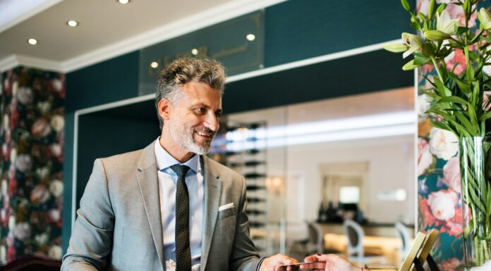 The Benefits of Full Fibre for UK Hospitality Businesses A man standing behind a desk giving a card back to a client