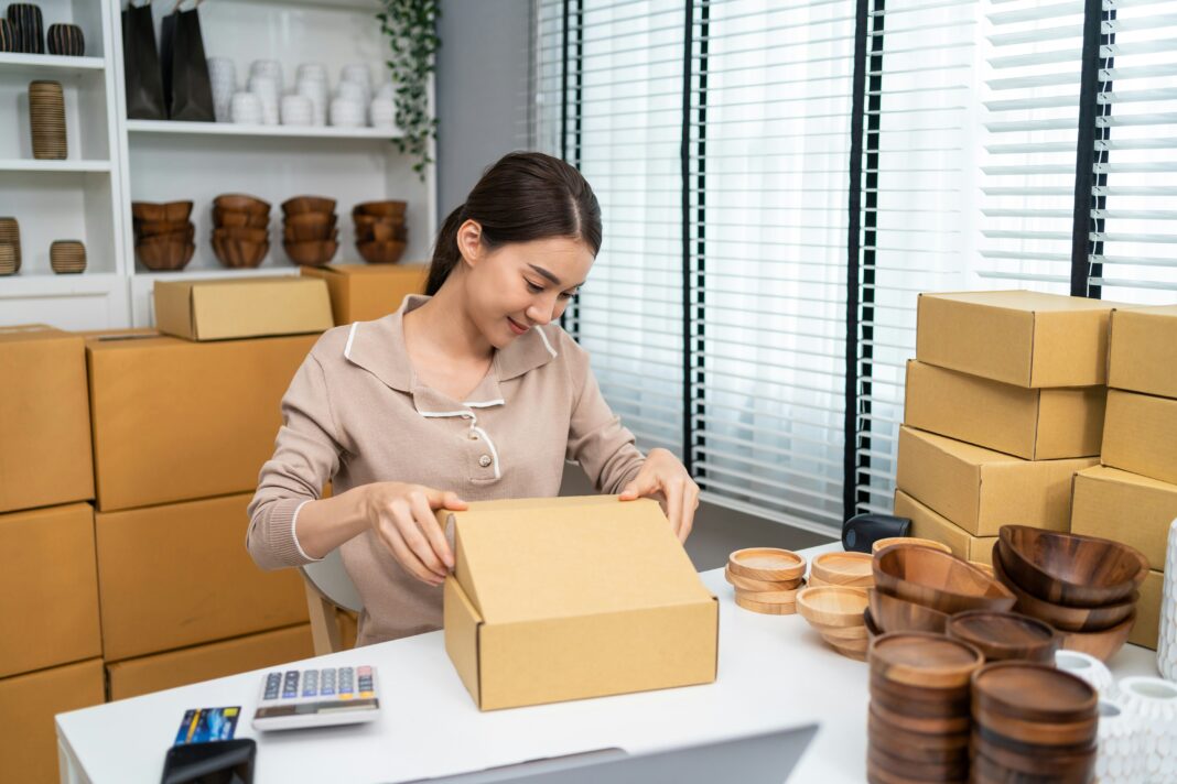 A woman sitting at her desk packing wooden bowls in to boxes.