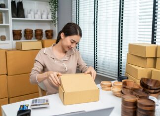 What Are the Key Features of VoIP Small Businesses Should Look For? A woman sitting at her desk packing wooden bowls in to boxes.