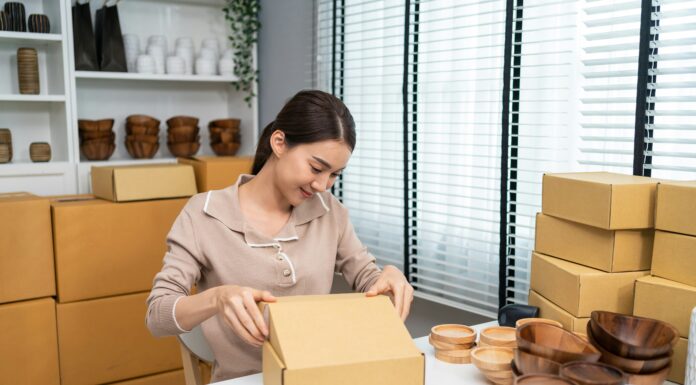 What Are the Key Features of VoIP Small Businesses Should Look For? A woman sitting at her desk packing wooden bowls in to boxes.