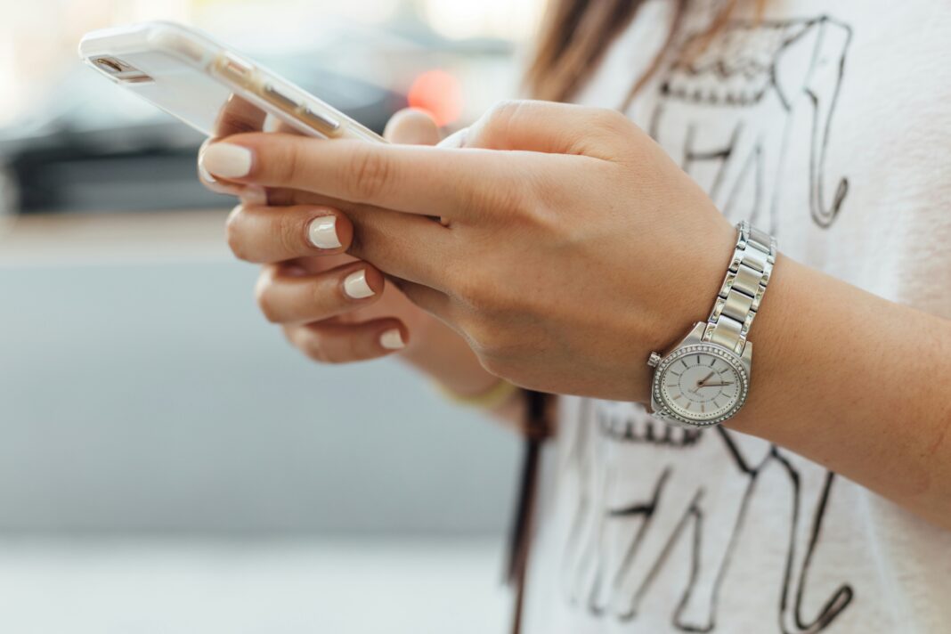 What Are the Main Benefits of Using a Dumb Phone? A woman wearing a silver watching typing on a white phone