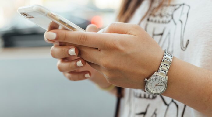 What Are the Main Benefits of Using a Dumb Phone? A woman wearing a silver watching typing on a white phone