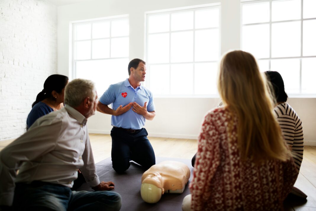What Role Does Broadband Connectivity Play in Disaster Preparedness? A group of people sitting in a room in front of a cpr instructor