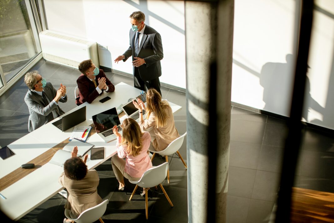 Aerial view of an office with people sitting around a table talking