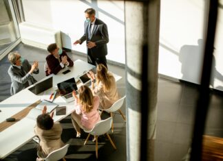 Which Companies Offer The Best Full Fibre Deals? Aerial view of an office with people sitting around a table talking