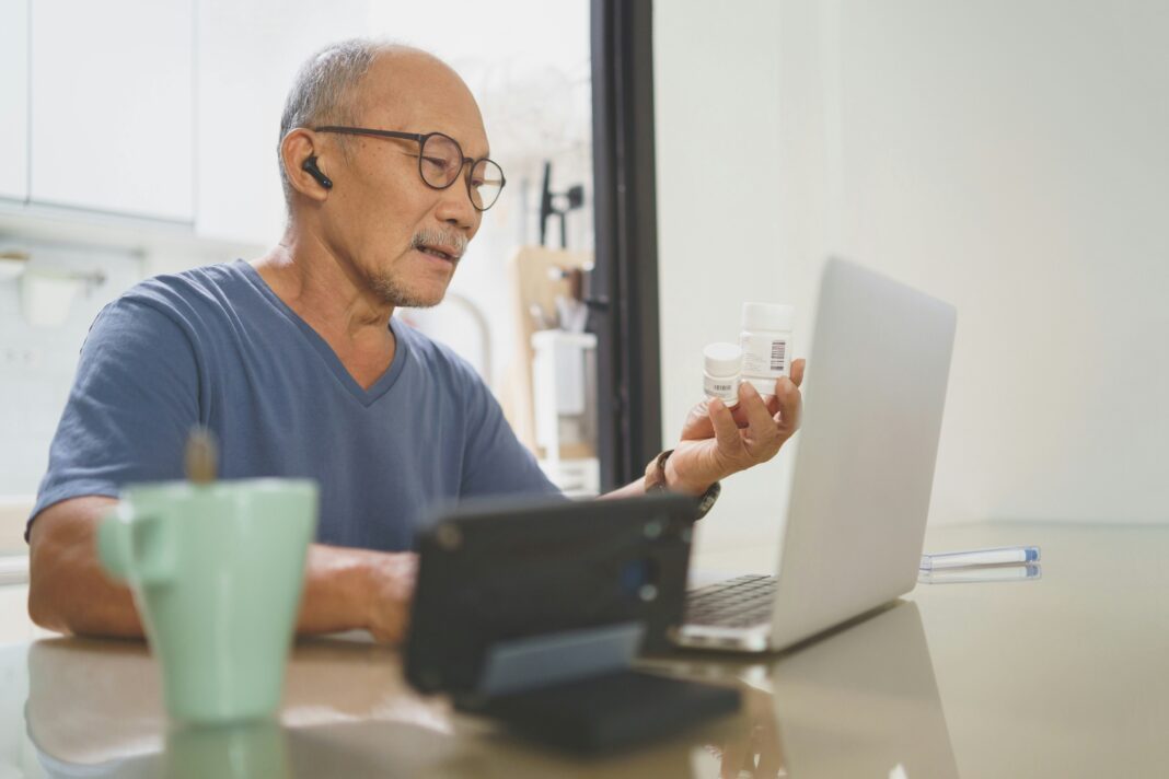 A man sitting at his laptop with earphones and a mug of coffee