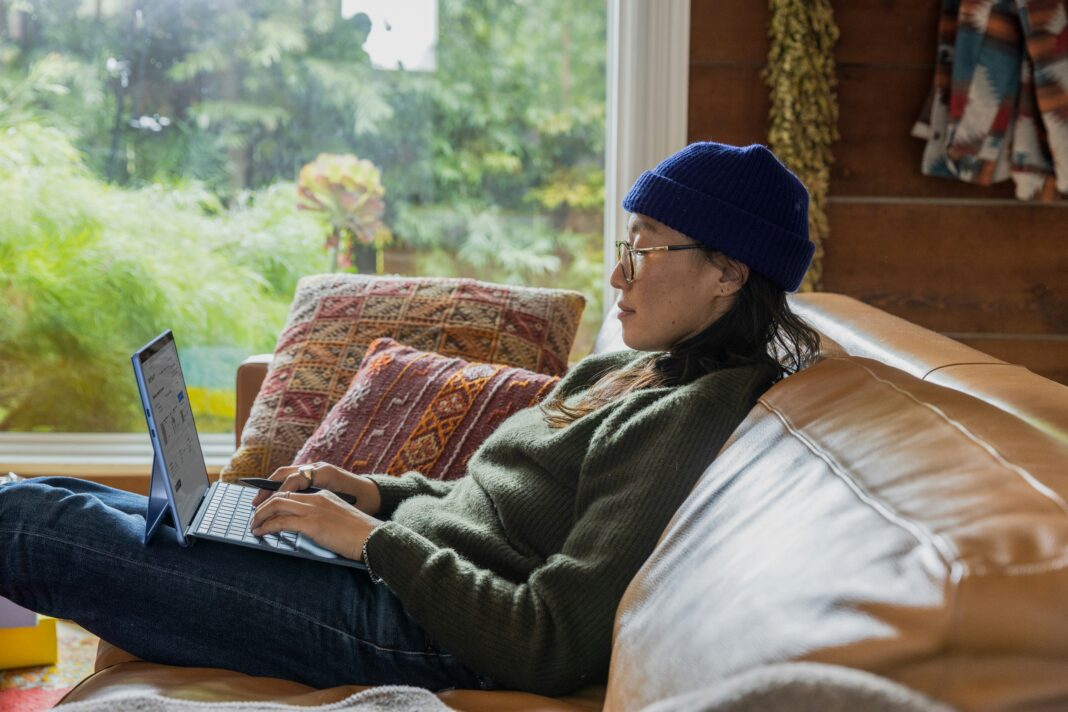 A woman sitting on a couch working on her laptop