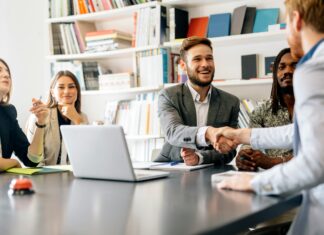 5 Reasons Your Business Broadband is Running Slow A group of people sitting around an office table smiling and shaking hands