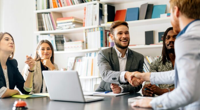 5 Reasons Your Business Broadband is Running Slow A group of people sitting around an office table smiling and shaking hands